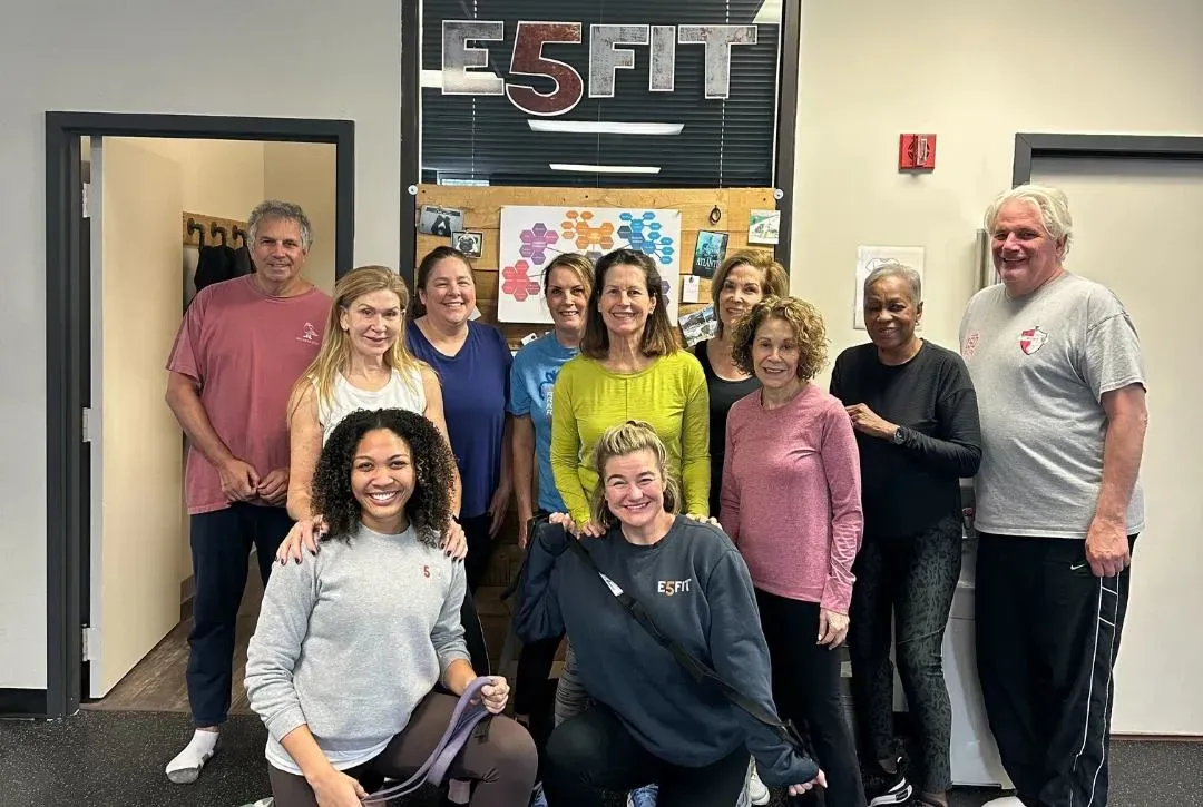 Group of diverse adults posing together in a fitness studio